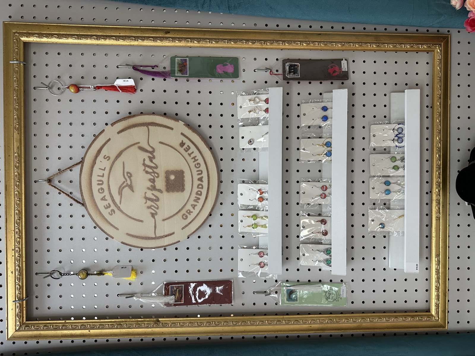 Framed display of decorative hatpins and Art Postal branded signage