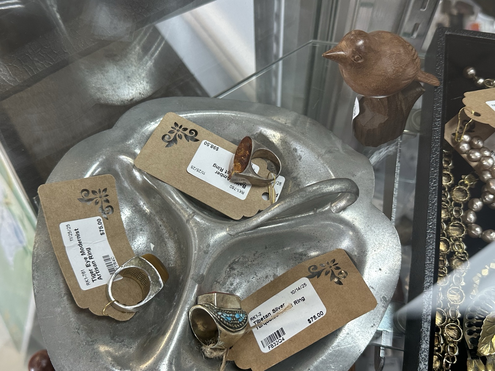 Vintage rings on a silver tray with a small carved bird figurine
