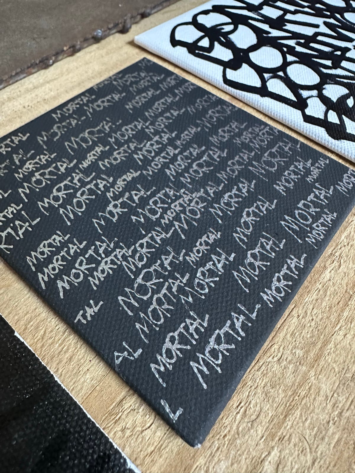 Repeated-text MORTAL fabric pieces and black and white graphic art