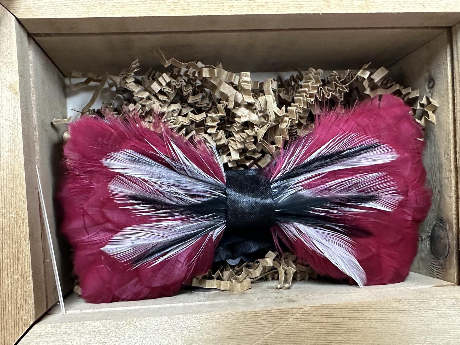 Handmade feather bow tie with burgundy and black-and-white feathers in a wooden gift box