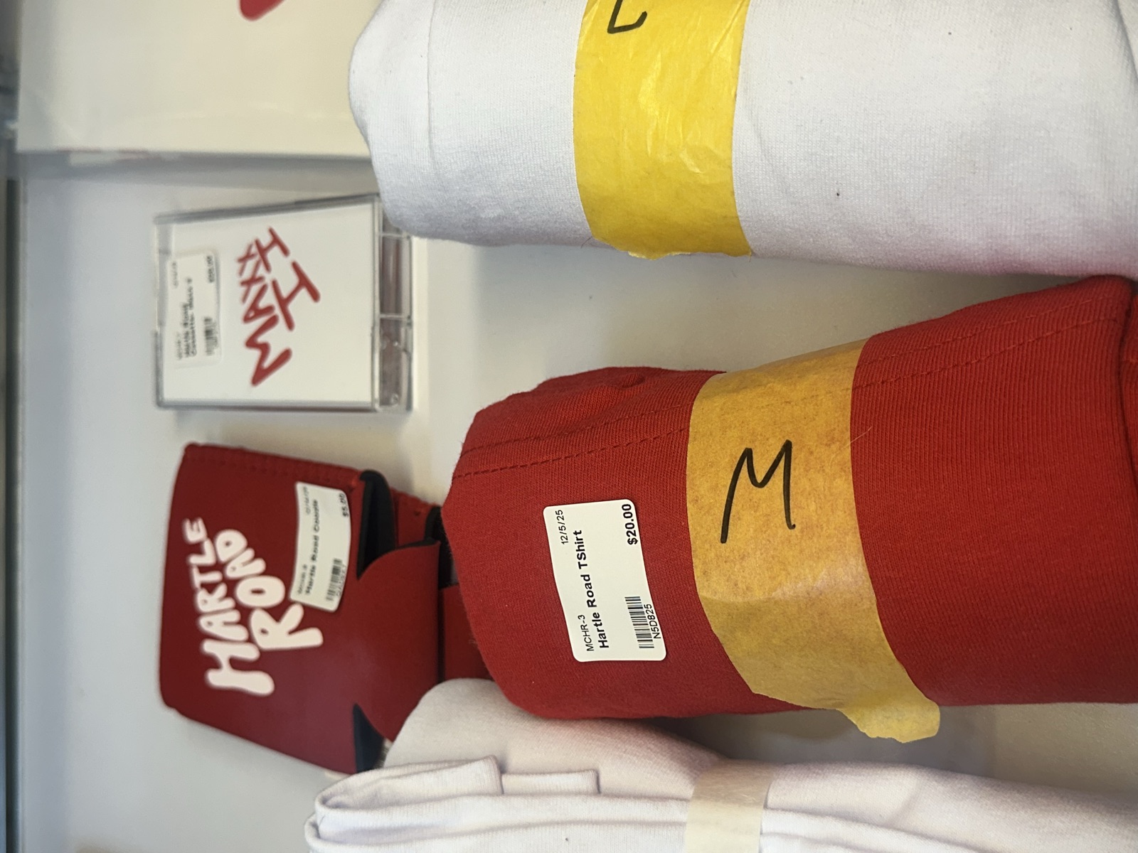 Hartleroad band merch display with t-shirts, koozies, and CDs