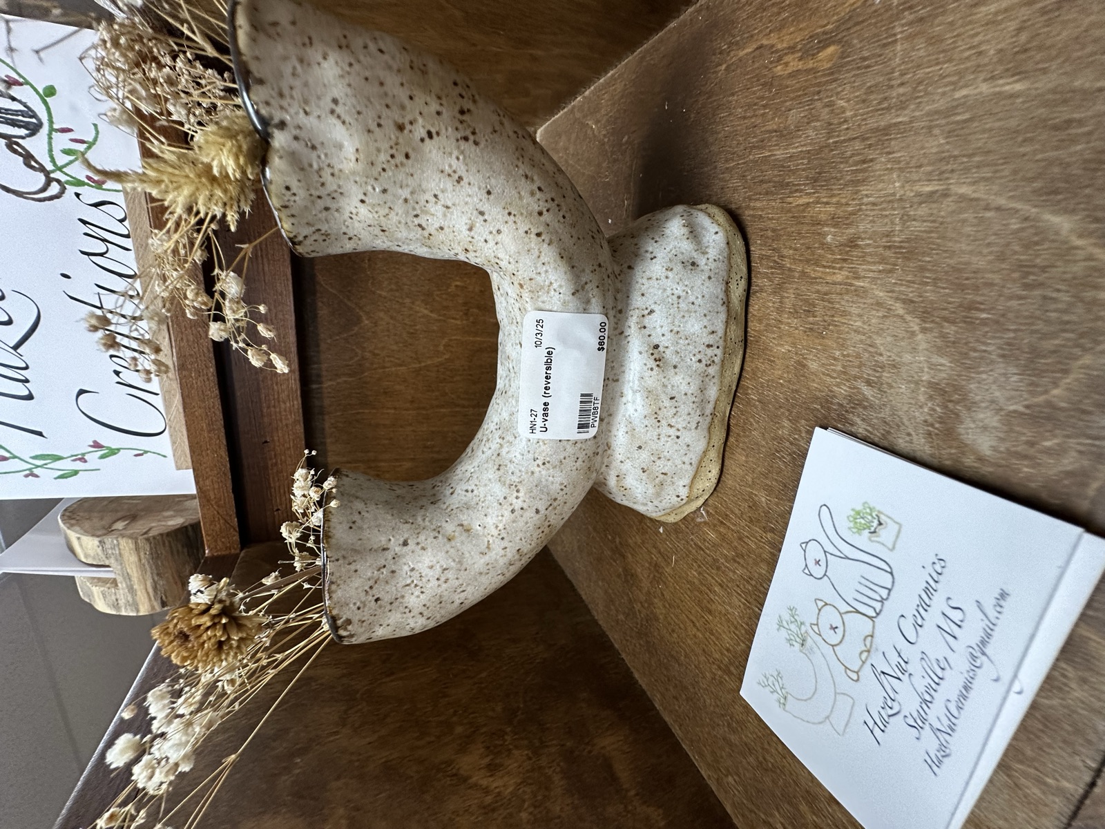 Speckled ceramic ring vase on a wooden display shelf