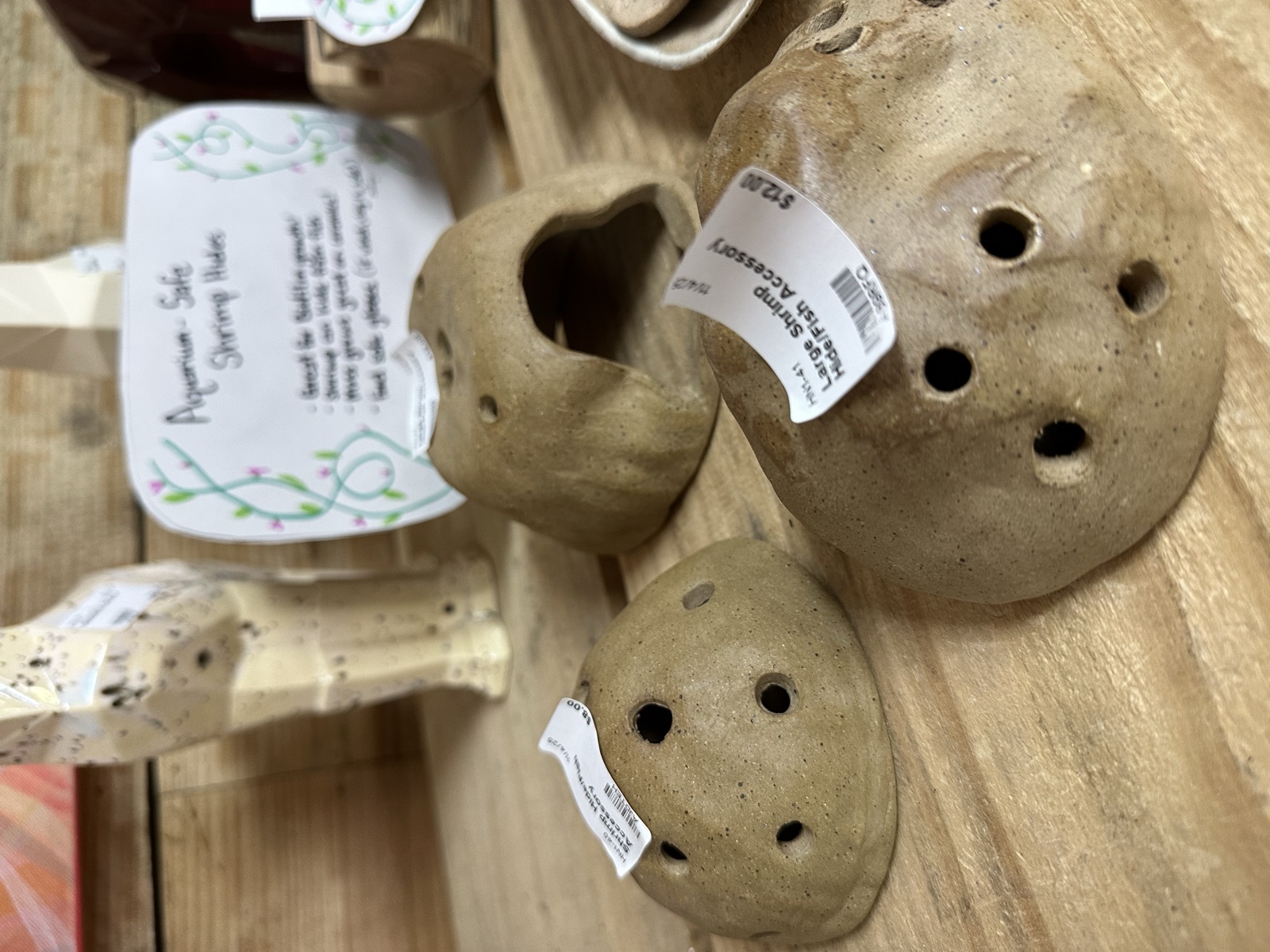 Handmade ceramic spray bottles and small rounded vessels on a wooden shelf