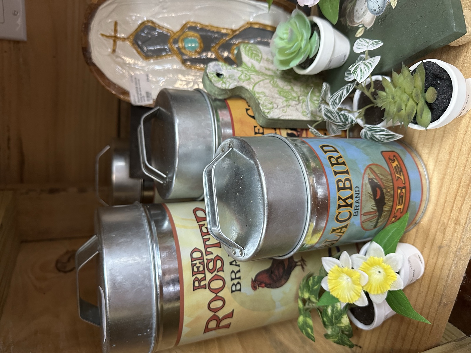 Vintage tin canisters repurposed as planters with faux flowers and greenery
