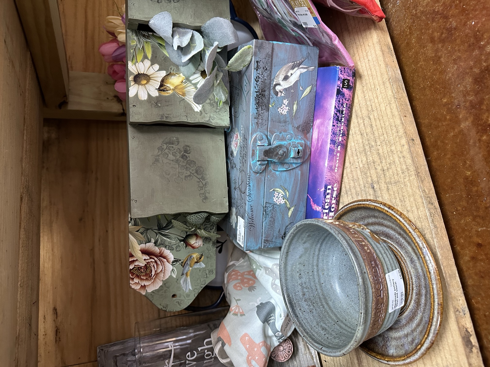 Assorted floral decorative boxes, vintage tins, and containers on a wooden shelf