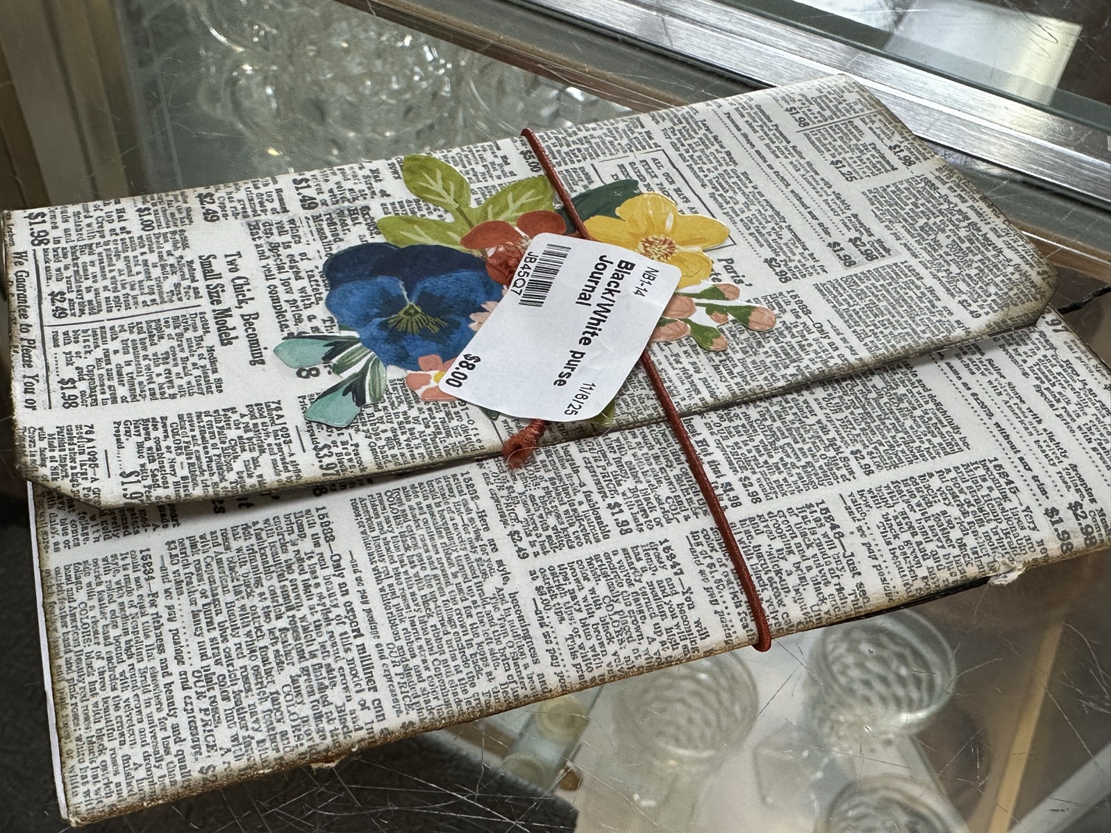 Newspaper-print purse journal with pressed flower embellishment and leather cord closure