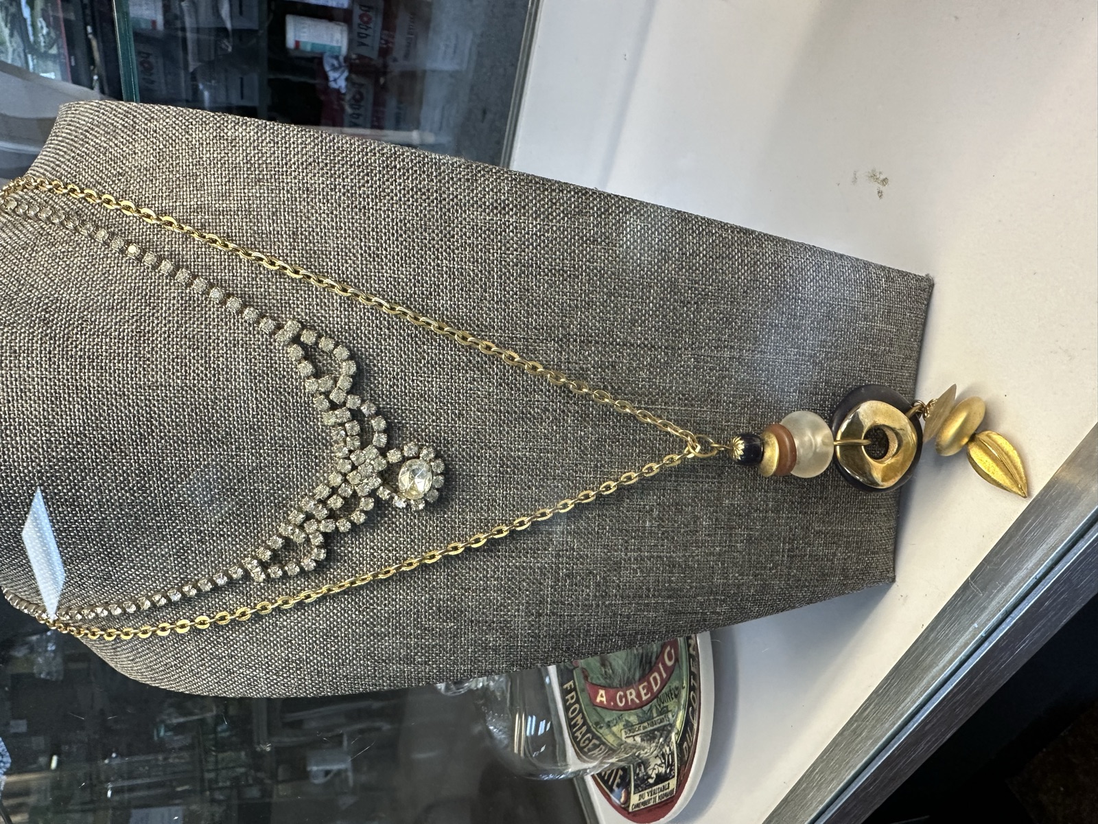 Layered vintage rhinestone necklace and gold chain with mixed beads on display