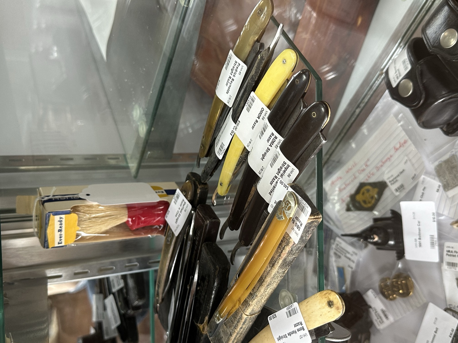 Collection of vintage straight razors with colored handles on a display rack